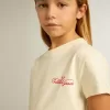 T-shirt da bambina in cotone bianco consumato con ricamo rosso sul petto