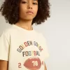 T-shirt da bambino in bianco consumato con scritte multicolori